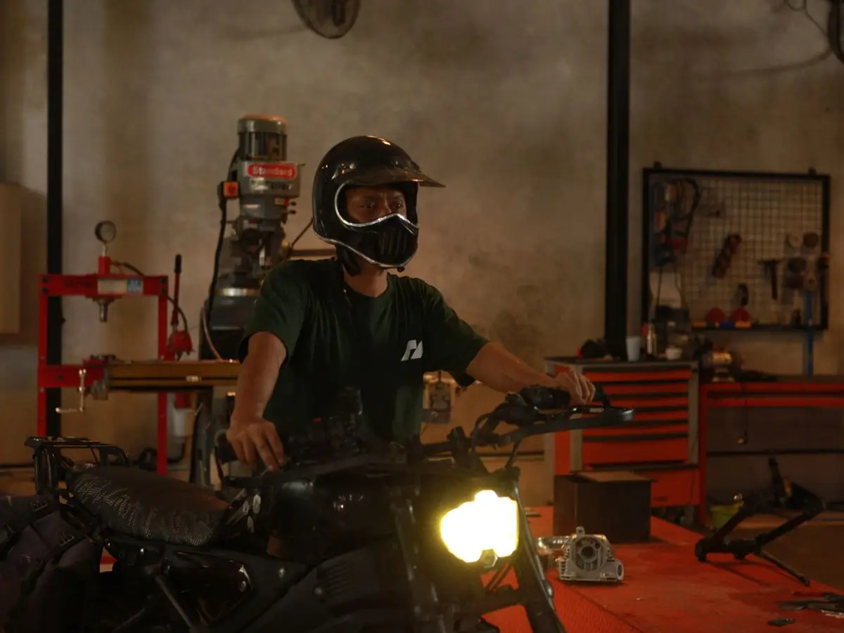 A rider in a helmet on a finished bike, headlight on
