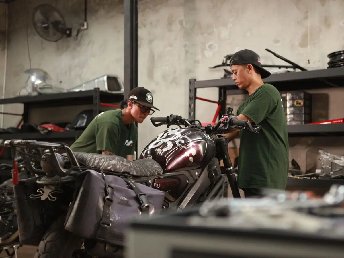 Two mechanics working on a maroon custom