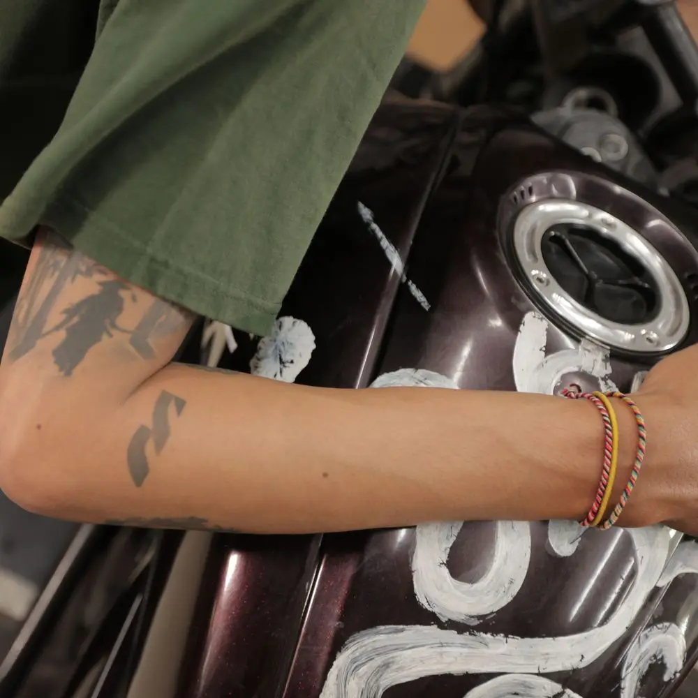Hand-lettered paint on a dark tank, an arm across the frame