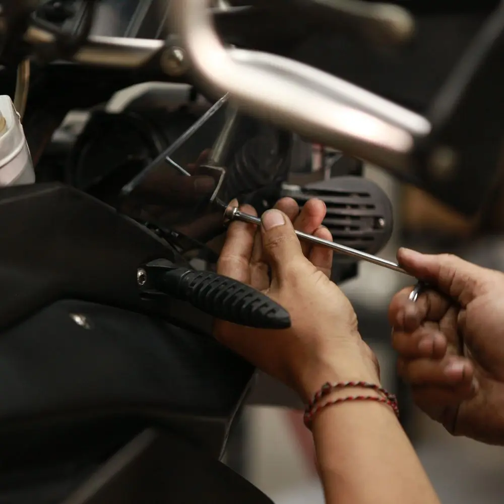 Hands holding a small hand tool over a bike part